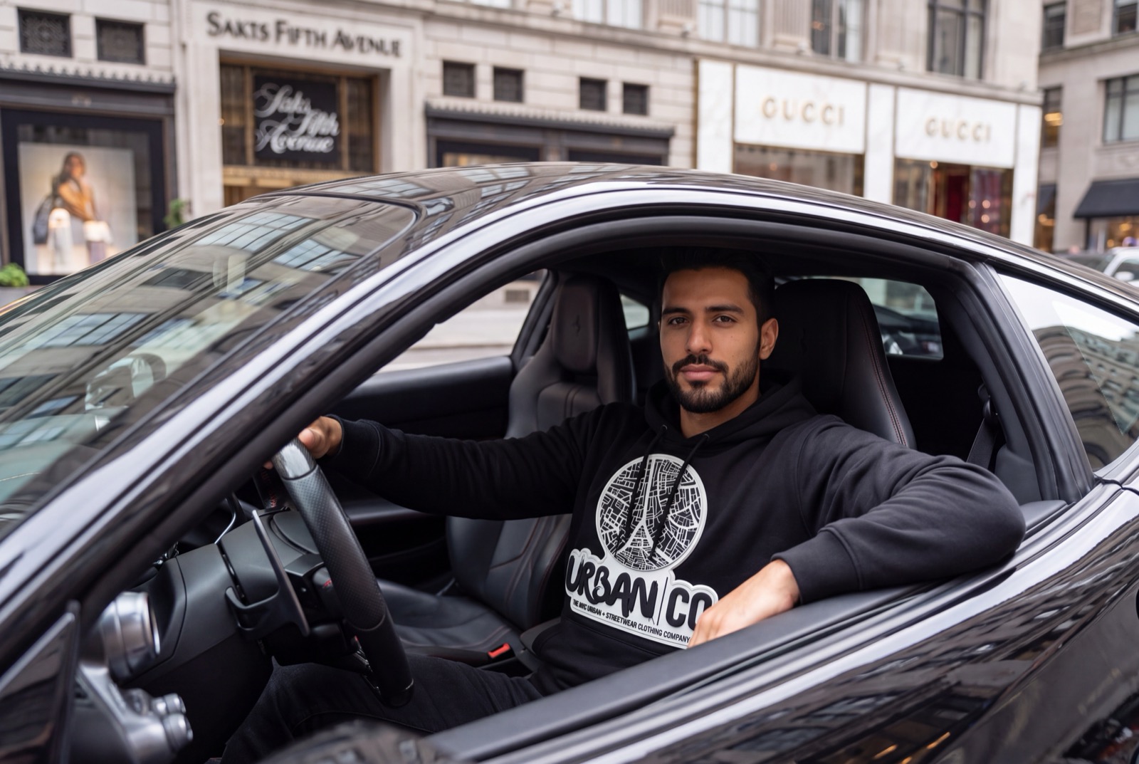 Man wearing an Urban Co. black hoodie driving on Fifth Avenue